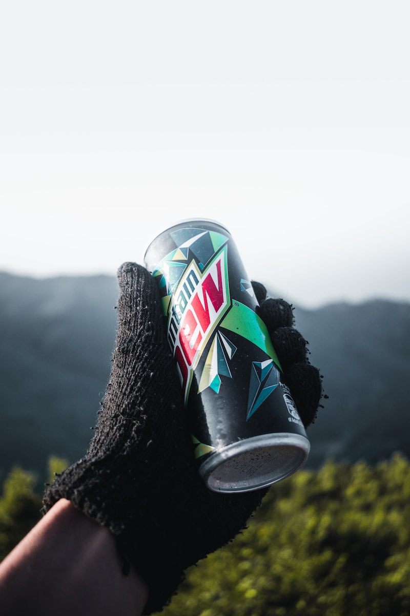 a hand holding a can of wnc on top of a mountain