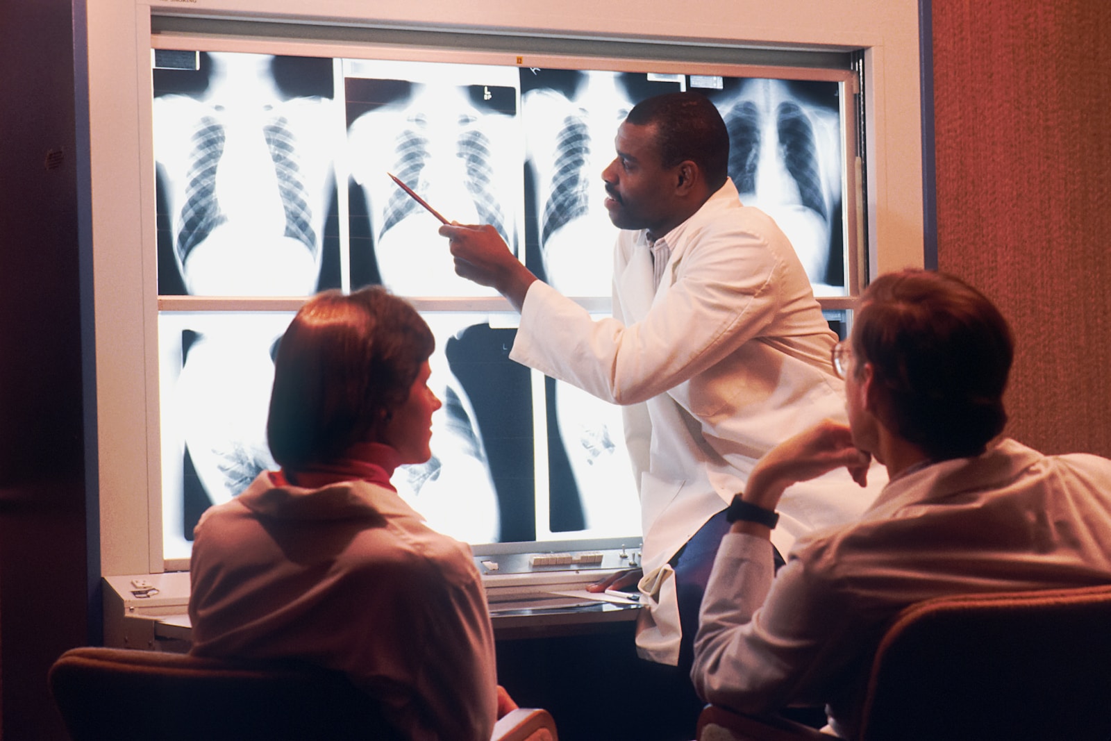 a man in a white lab coat pointing to an x - ray